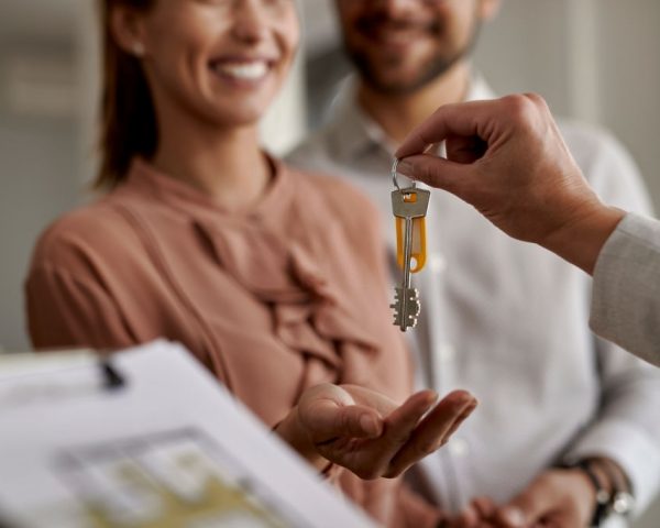 Close-up of real estate agent giving new house keys to a couple.